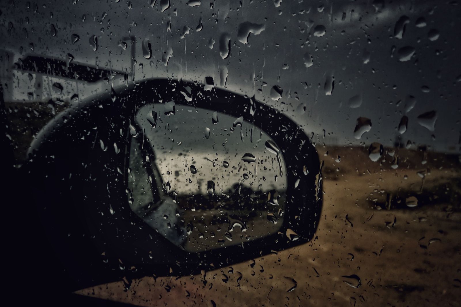 車窗玻璃與車外後視鏡上布滿雨滴的近照